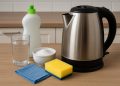Electric kettle being cleaned with vinegar and sponge on a kitchen countertop